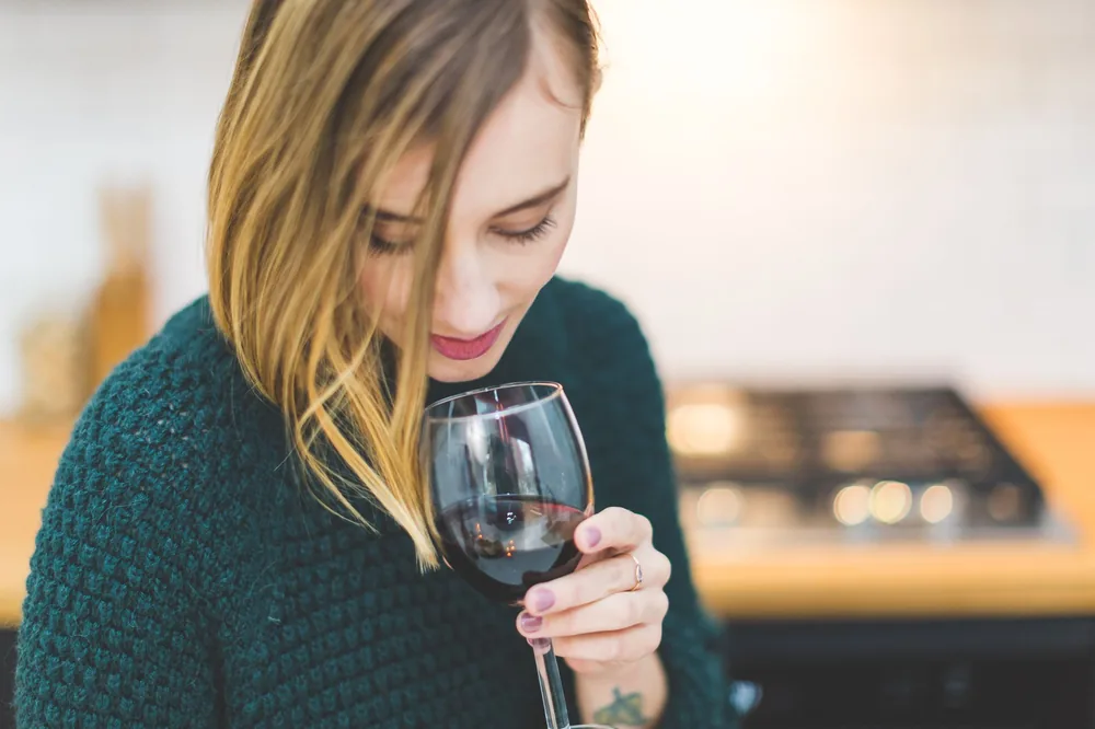 A young woman savoring a glass of red wine in a cozy indoor setting, capturing the essence of relaxation and leisure