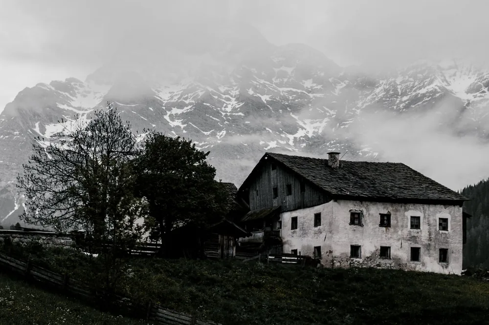 Abandoned farmhouse in the mountains shrouded in fog, creating a mysterious winter landscape
