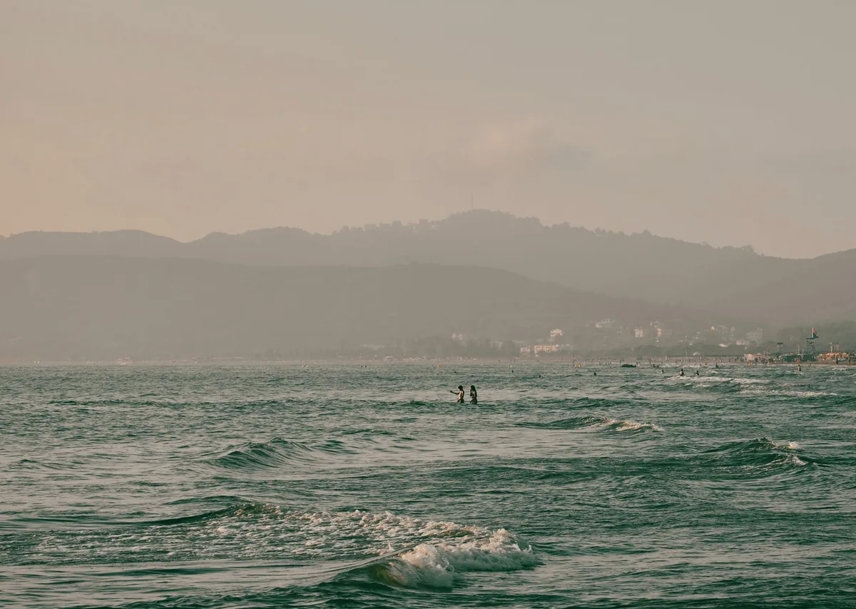 Gentle waves roll onto the Durres beach with mountains in the backdrop