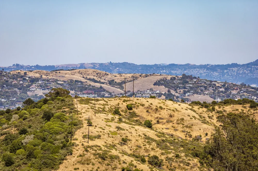 Aerial landscape of rolling golden hills with residential areas in the distance