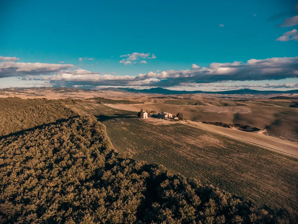 Aerial shot capturing the expansive Tuscan countryside under a blue summer sky