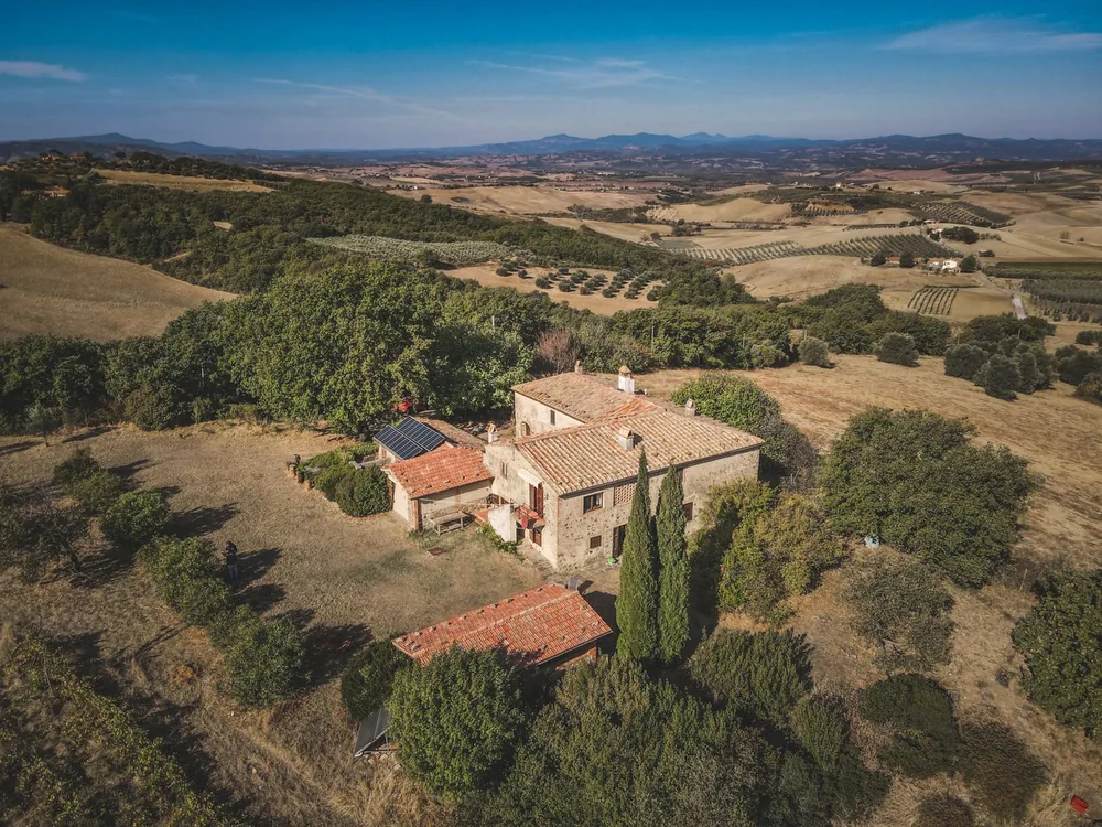 Aerial shot of a stone house surrounded by lush countryside and rolling hills