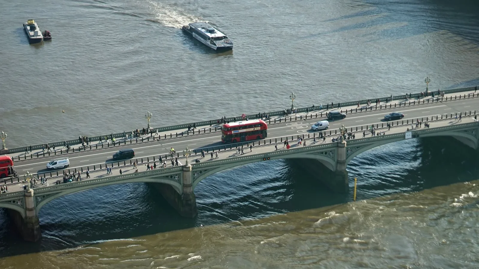 Aerial shot showcasing traffic and pedestrians on a London bridge over the River Thames