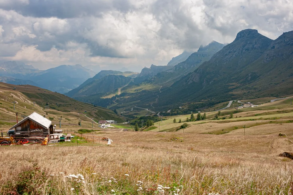Alpine valley landscape featuring a rustic farmhouse surrounded by mountains