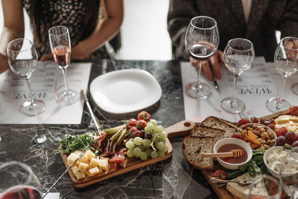 An elegant dining setup featuring glasses of wine and a cheese platter on a marble table