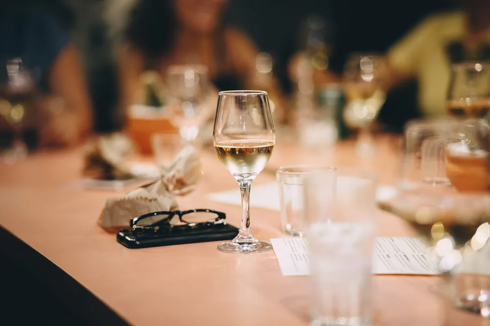 An elegant indoor gathering featuring white wine glasses and soft lighting on a table