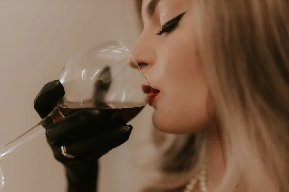 An elegant woman sipping a glass of red wine, showcasing glamour and style