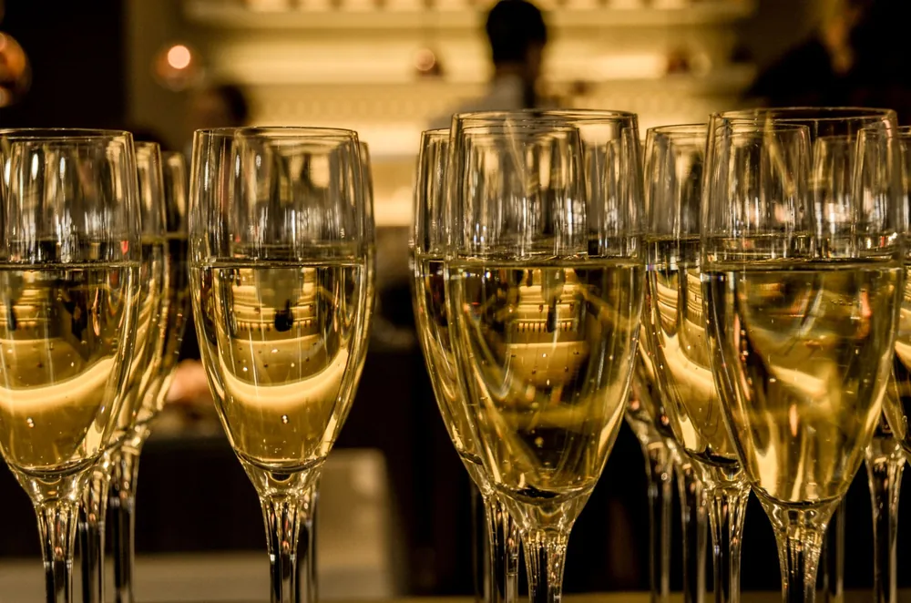 Array of filled champagne glasses in a luxurious indoor setting, ready for celebration