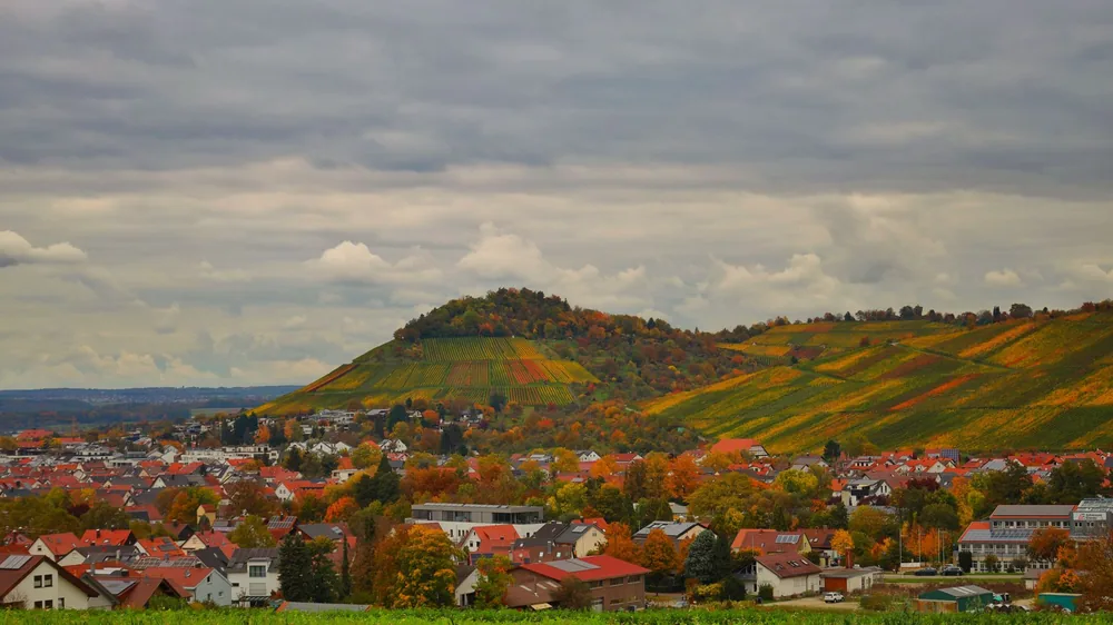 Autumn scene with rolling hills and a village under clouded sky