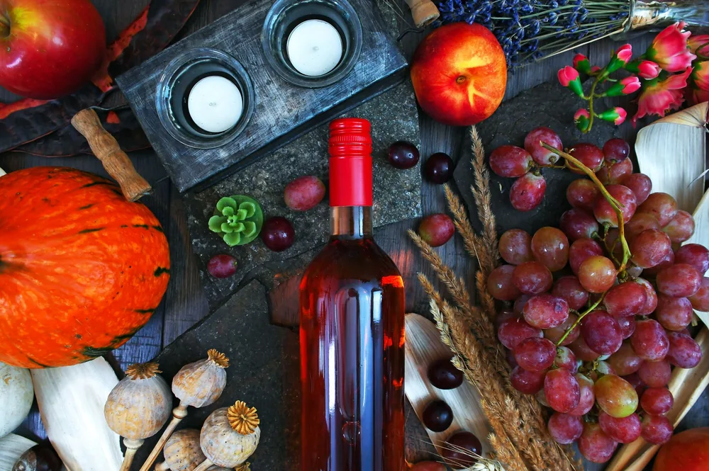 Autumn-themed still life featuring wine, fruits, and candles