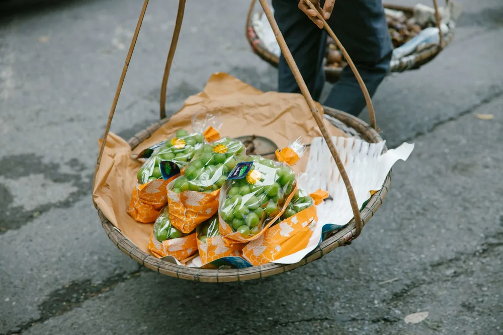 Bamboo basket with green grapes in street market setting, evokes traditional food culture