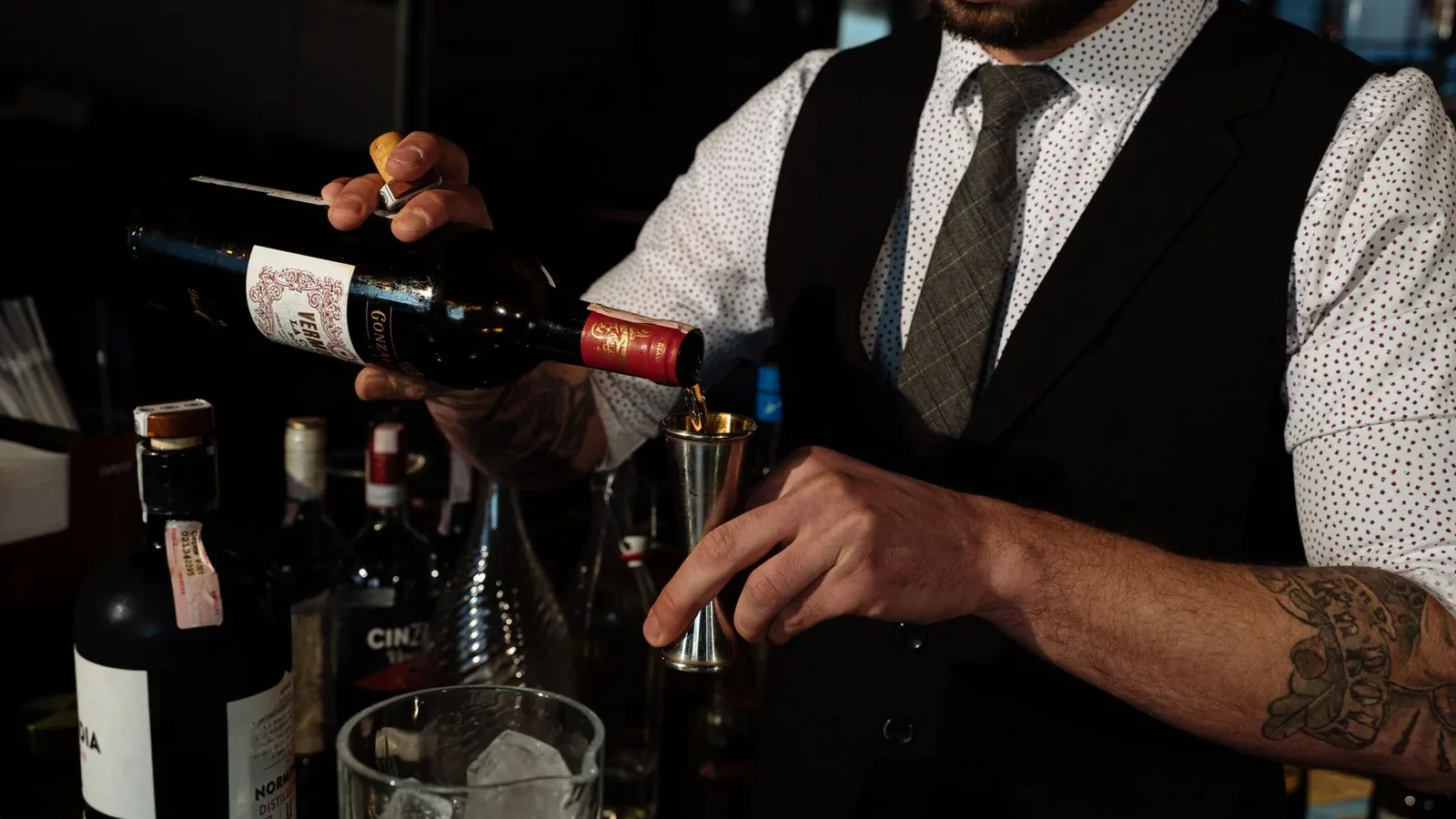 Bartender skillfully measures and pours red wine in a bar setting