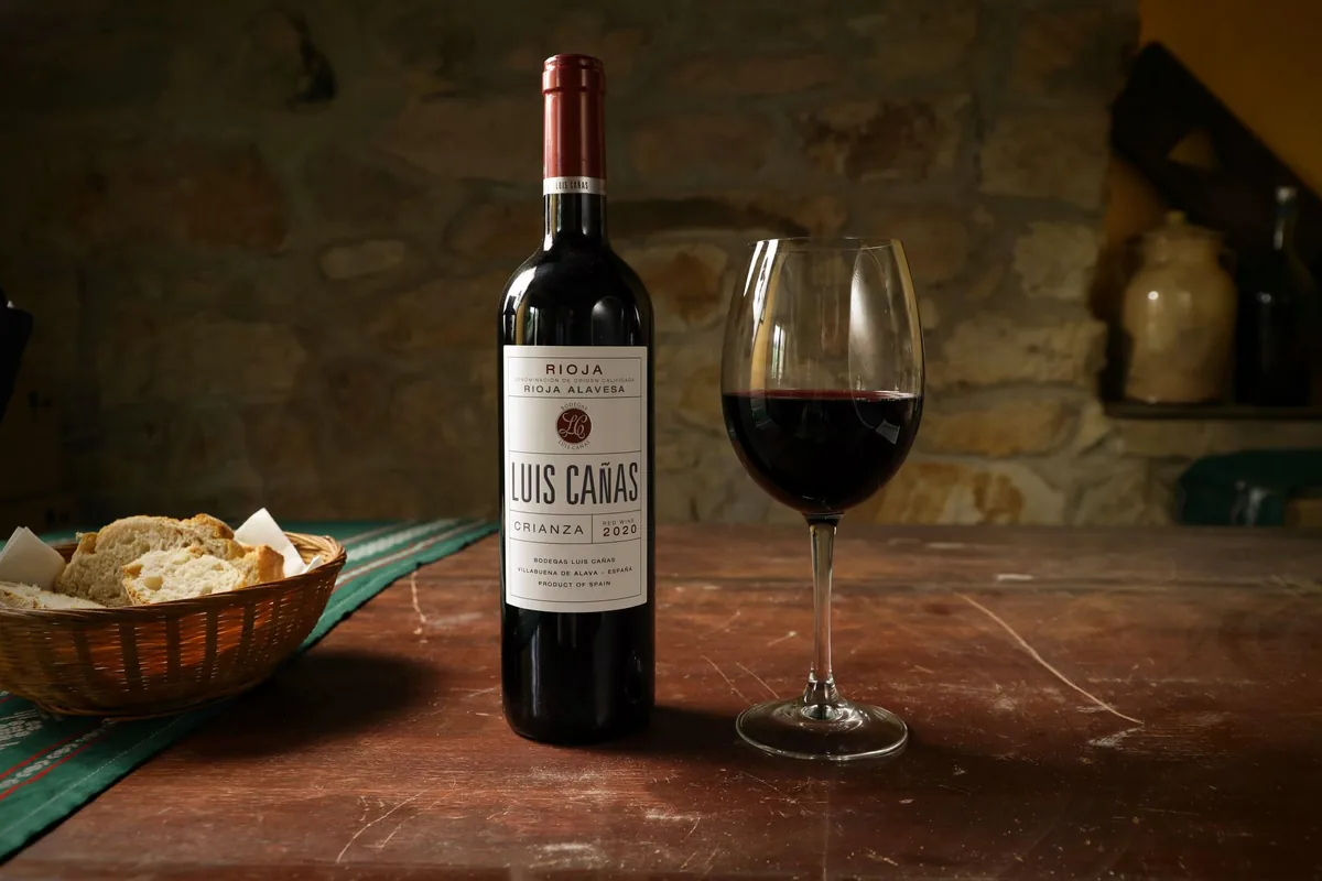 Luis Cañas wine bottle with a glass on a vintage wooden table, perfect for dining settings