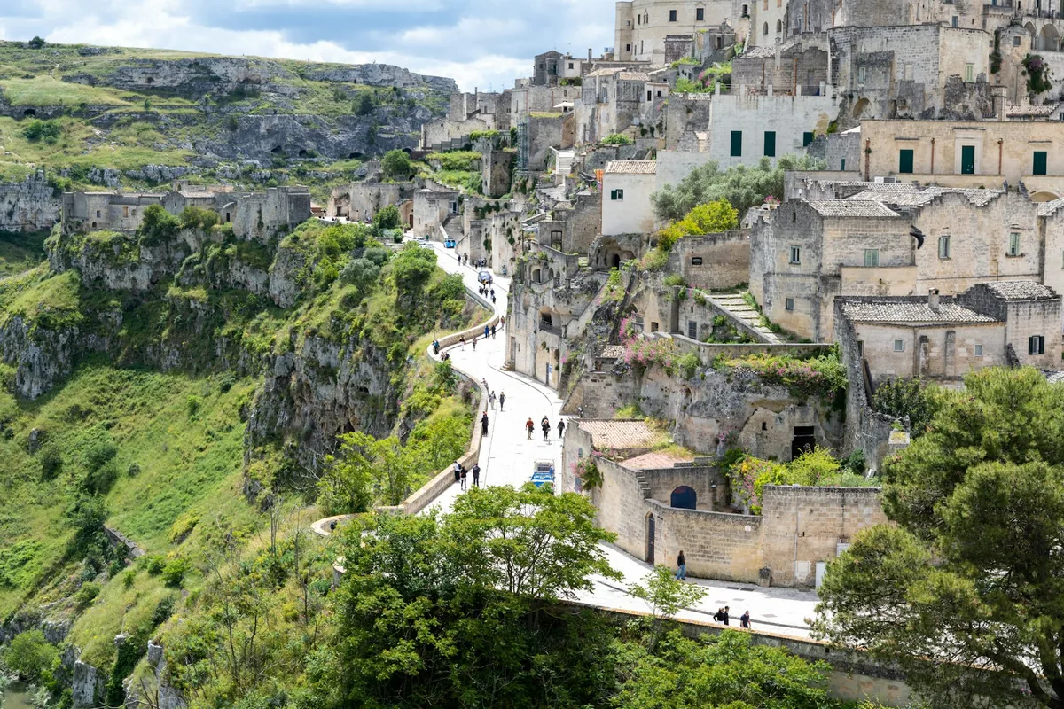 Historic stone city built into a green, rocky hillside