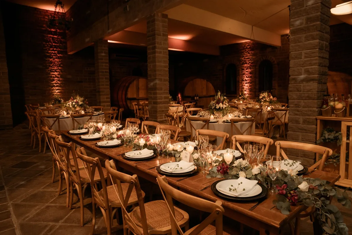 Beautifully set tables in a rustic winery for an elegant event with warm lighting and floral decor