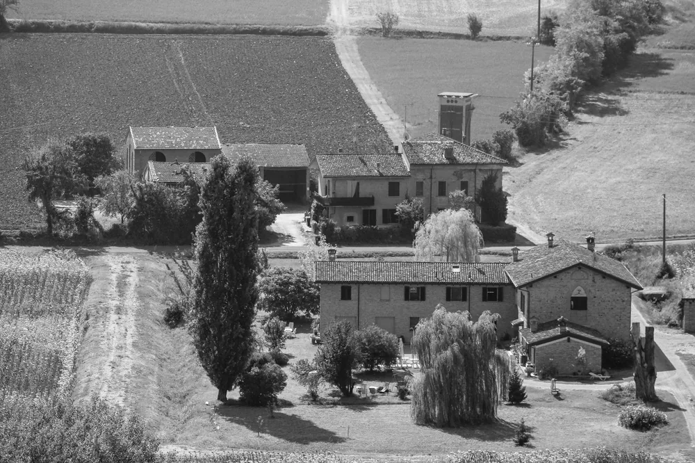 Black and white aerial photo of a rustic farmhouse surrounded by fields