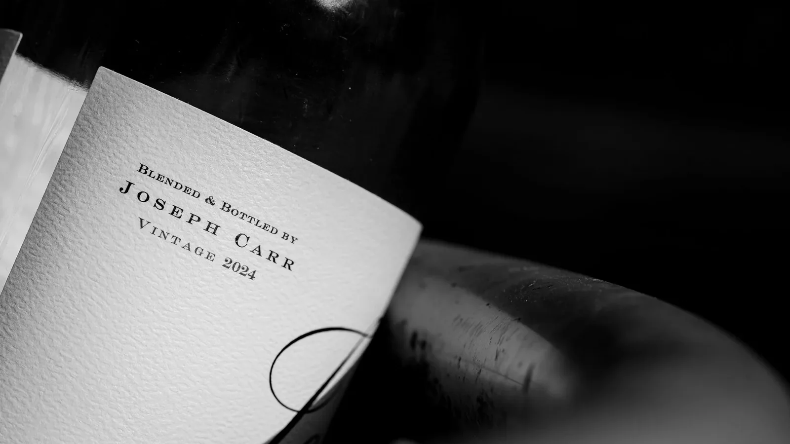 Black and white close-up of a wine bottle showcasing vintage label details