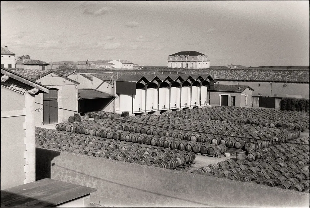 Black and white image of a historic winery with rows of wooden barrels outside