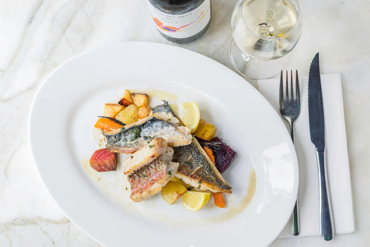 Fish dish paired with white wine, presented on a marble table setting
