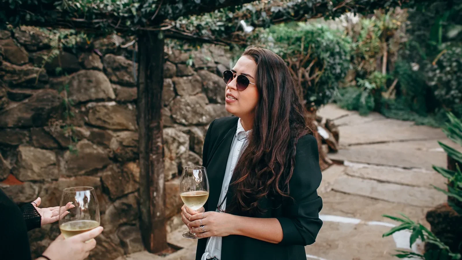 Casual outdoor gathering in a garden setting with wine and conversation among friends