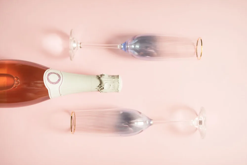 Champagne bottle with two glasses, styled on a pink background. Perfect for celebrations and elegant gatherings
