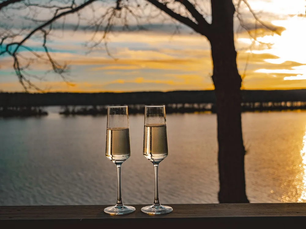 Champagne glasses capturing a serene sunset by the lake, perfect for romantic occasions