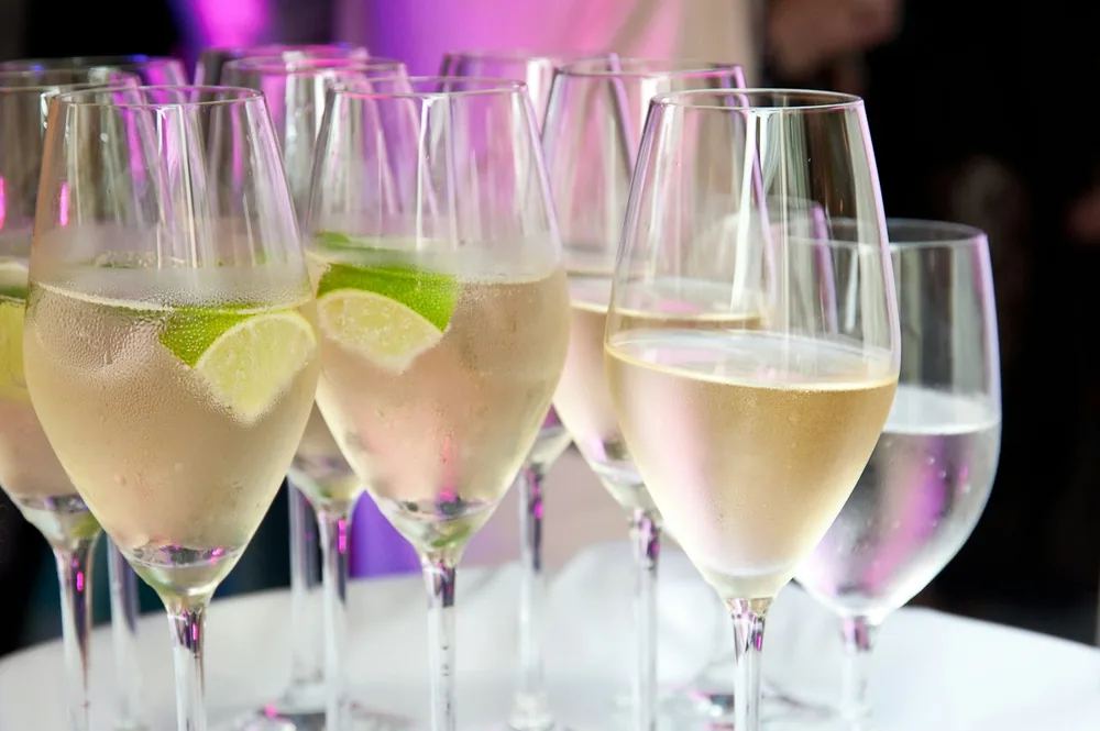 Champagne glasses with lime slices are displayed
