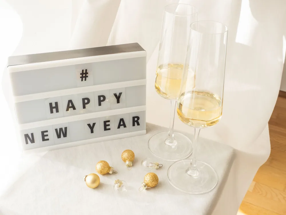 Cheerful New Year setup with champagne glasses and festive decor on a bright table