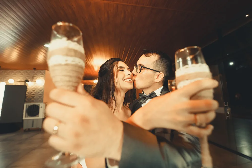 Cheerful newlyweds sharing a toast with dessert glasses during their wedding celebration