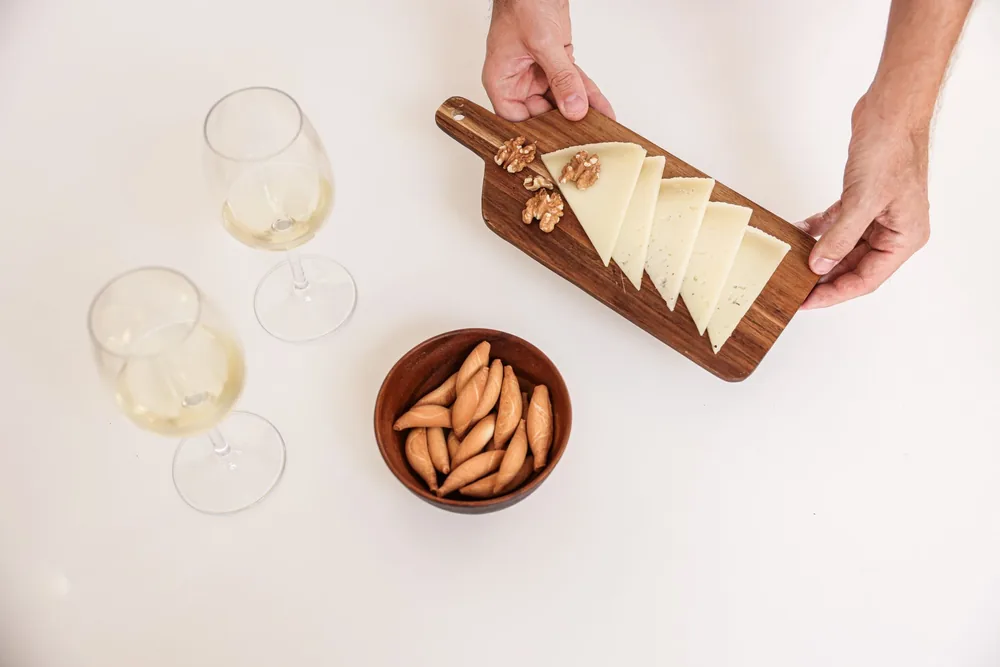 Cheese board with wine glasses and snacks on a white table. Perfect for entertaining