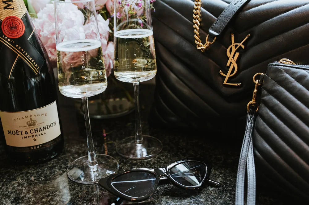 Chic setup featuring Moët & Chandon champagne, elegant bags, and glasses for a stylish evening