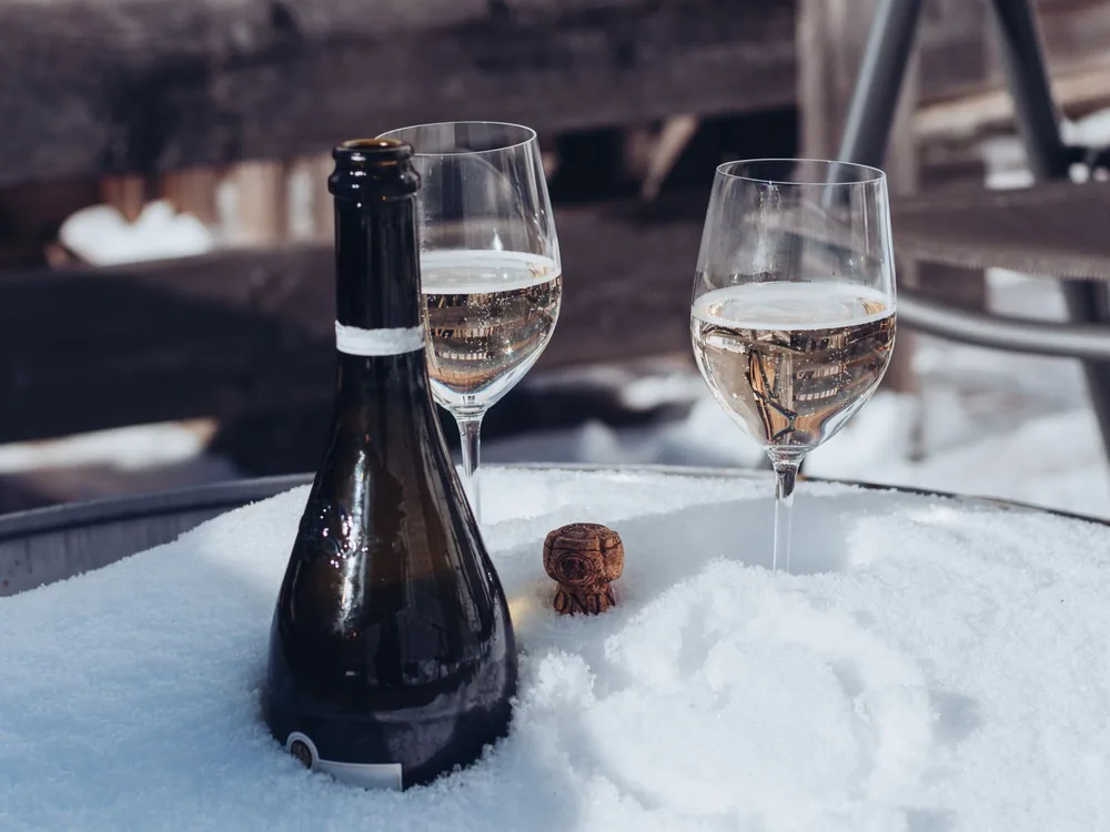 Chilled champagne bottle and glasses on a snowy table, perfect for a winter celebration