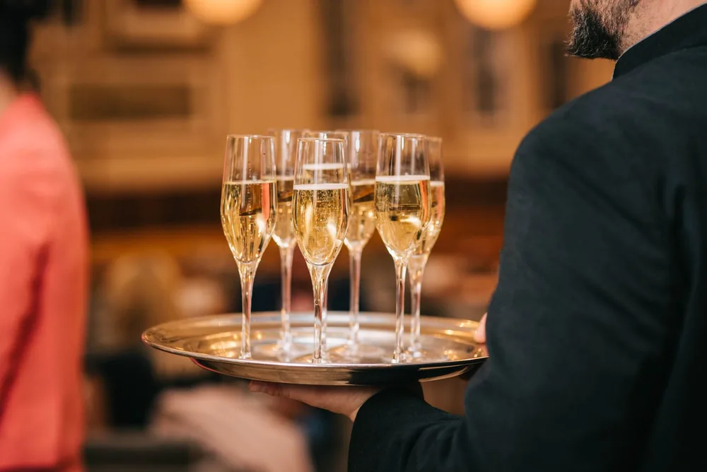 Classic image of a waiter carrying champagne glasses on a tray at a formal event