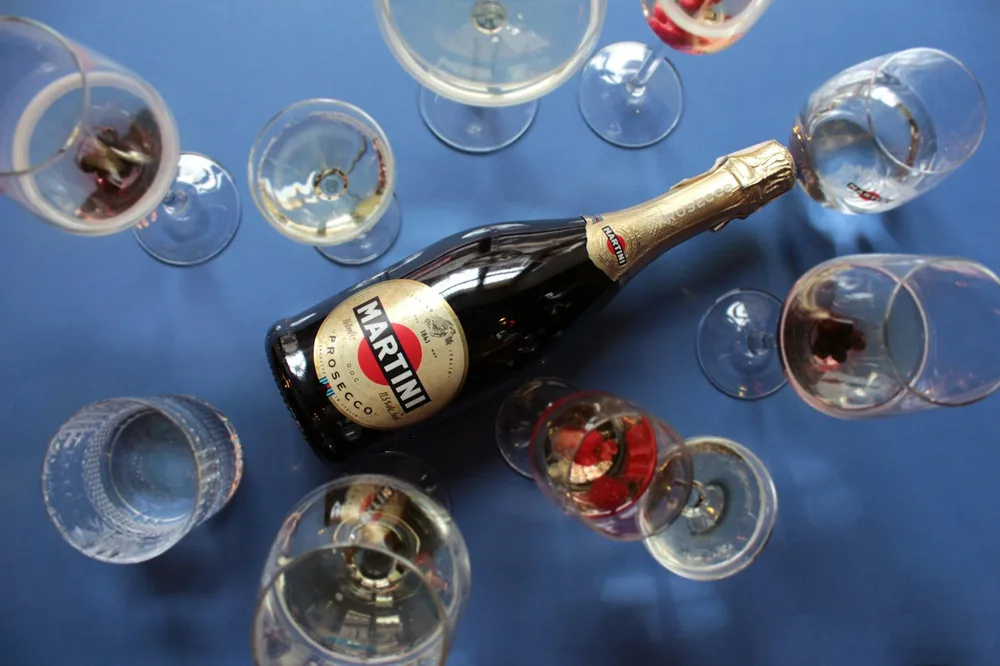 Clear wine glass beside white and red labeled bottle