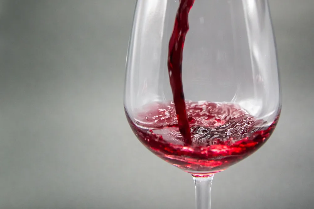 Close-up view of red wine being poured into a glass with artistic elegance