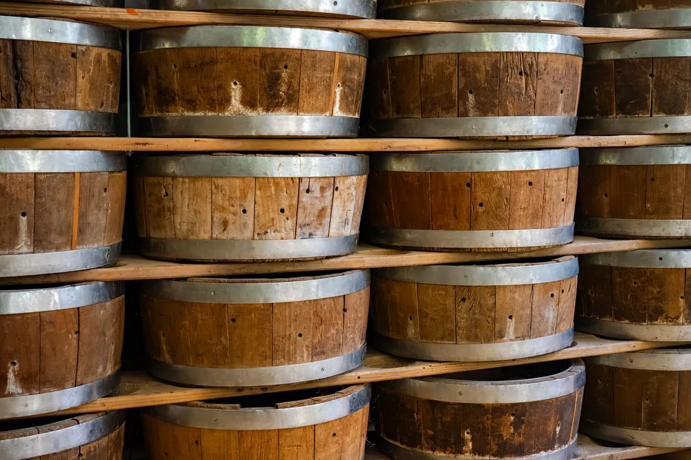 Close-up view of wooden barrels stacked on shelves inside a winery storage area