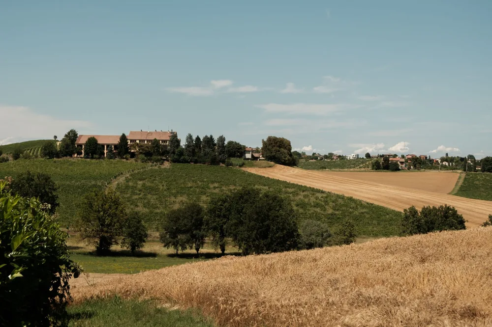 Countryside landscape featuring rolling fields, farmhouses, and clear skies