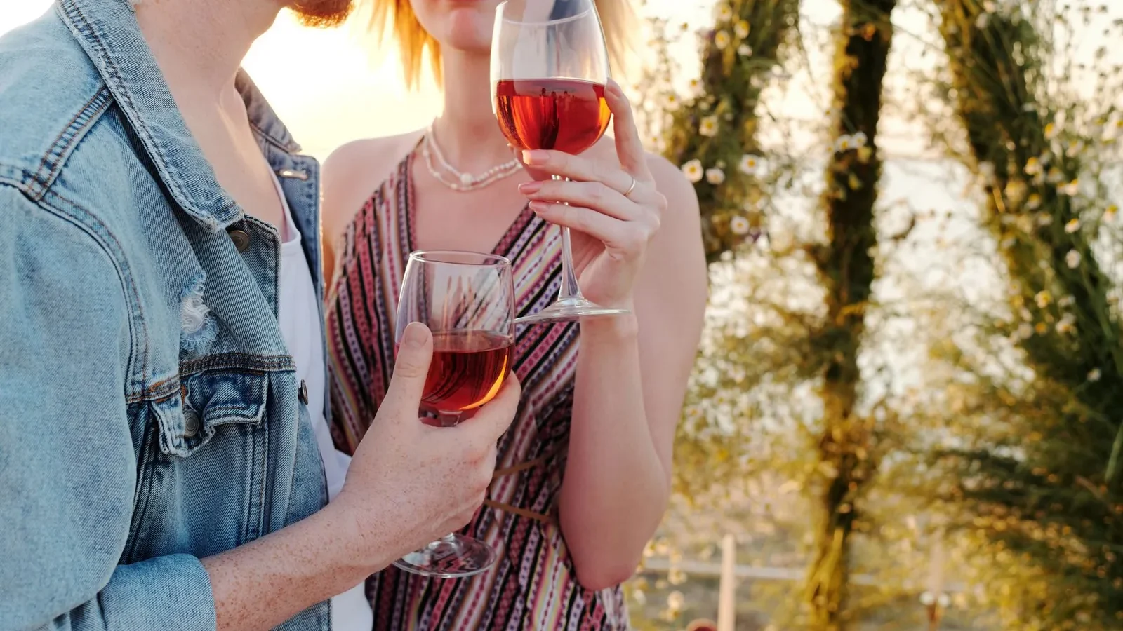 Couple toasting with wine glasses in a romantic outdoor setting at sunset