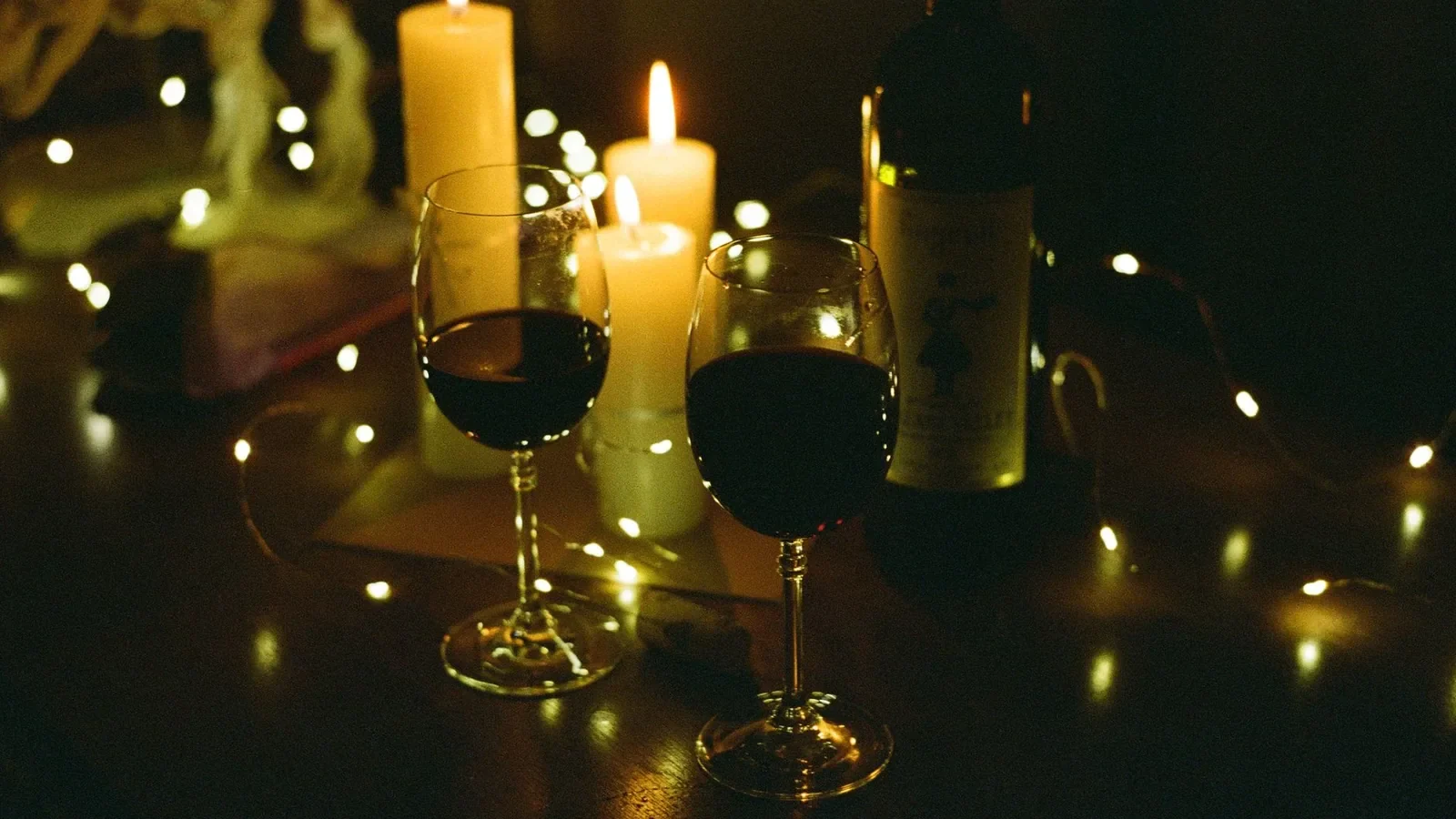 Cozy candlelit setting with wine glasses and bottle, perfect for romantic evenings