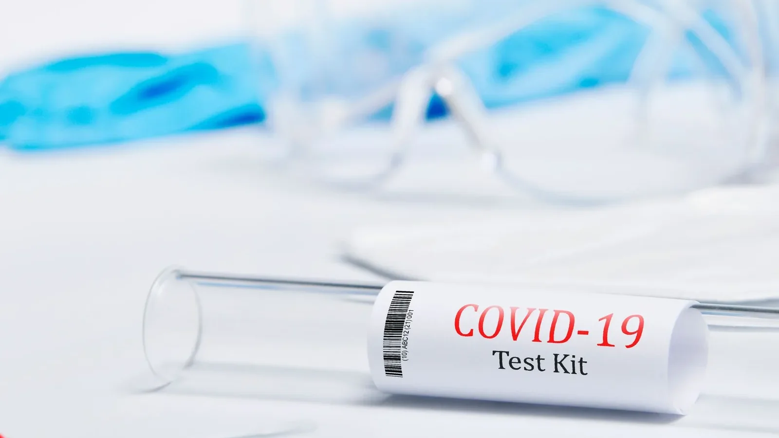 Detailed COVID-19 test kit with swab, gloves, and safety glasses on a white surface