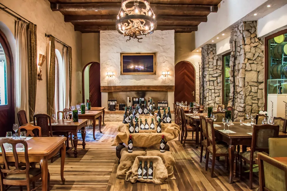Dining room with rustic decor, featuring wine bottles and elegant furnishings in a warm ambiance