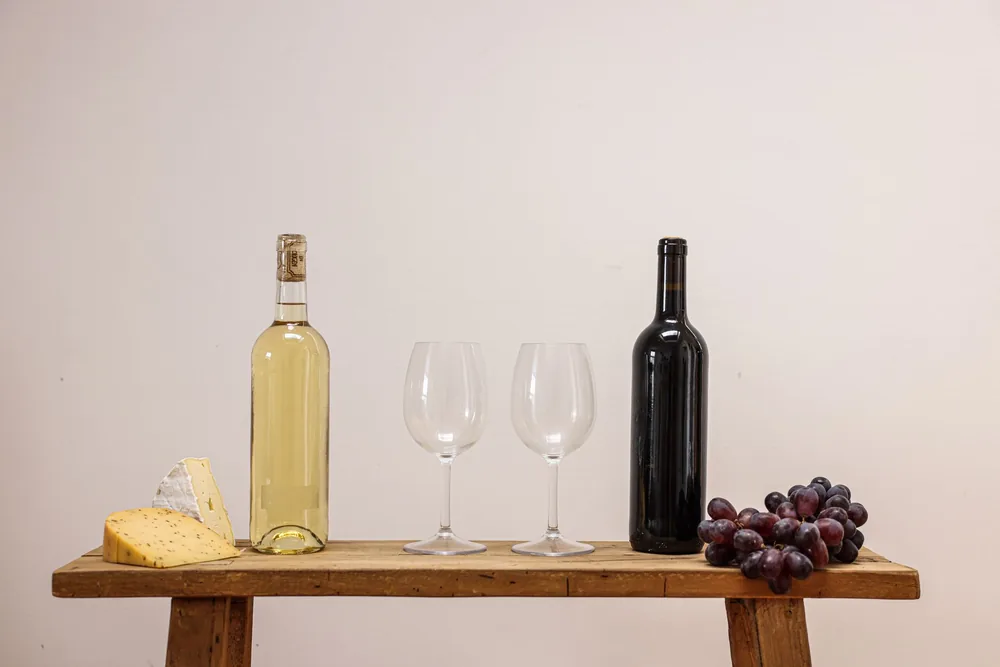 Display of wine, cheese, and grapes on a rustic wooden table