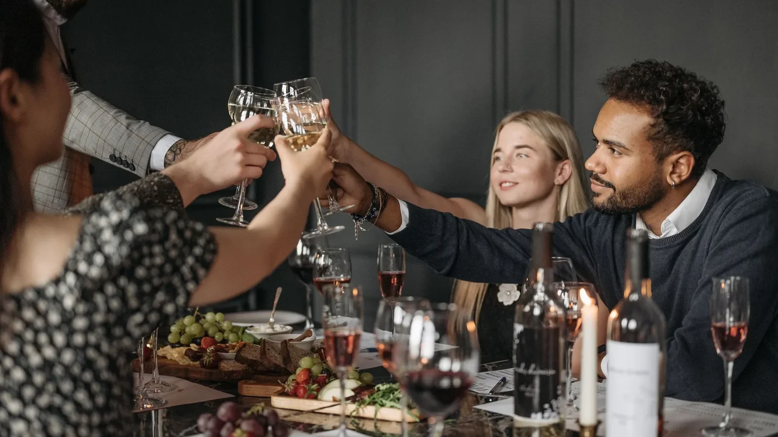 Diverse group enjoying a celebratory dinner with wine toasts and elegant table settings