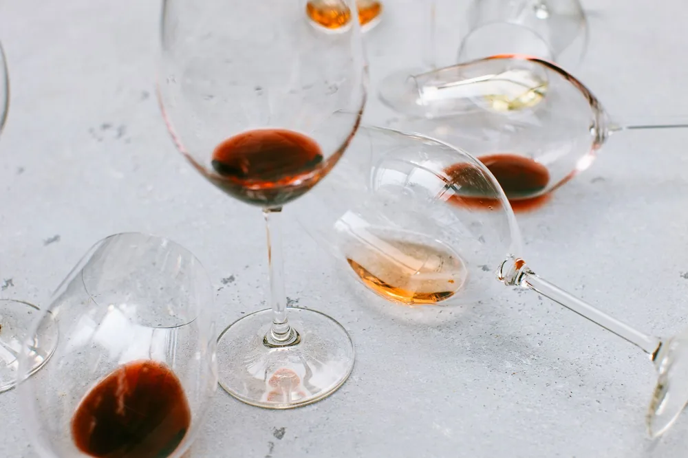 Empty and half-filled wine glasses scattered on a light surface, suggesting celebration