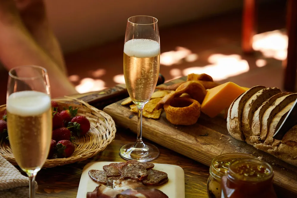Enjoy a gourmet selection of cheese, meats, and fruits paired with sparkling wine on a wooden board