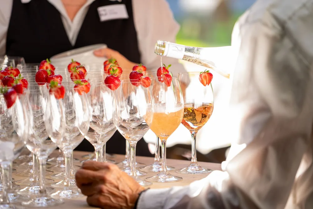 Event with glasses of champagne and strawberries, expertly poured by waiter