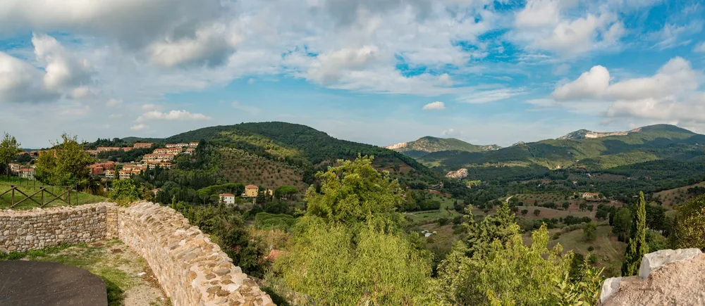 Explore a hillside town surrounded by lush greenery under a bright blue sky