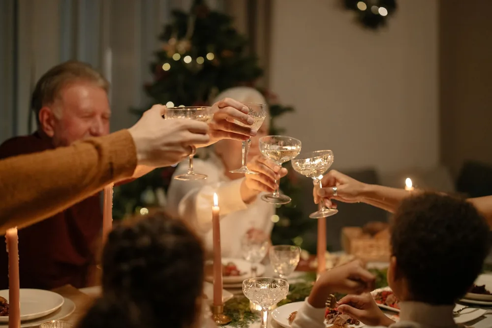 Family toasting with champagne glasses during a cozy holiday dinner by candlelight