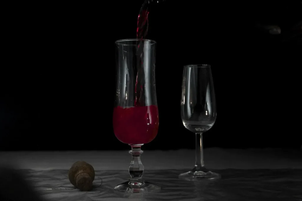 Red wine being poured into a glass against a dark background