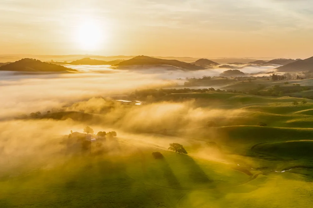 Foggy hills during sunrise, with golden light cascading over the landscape